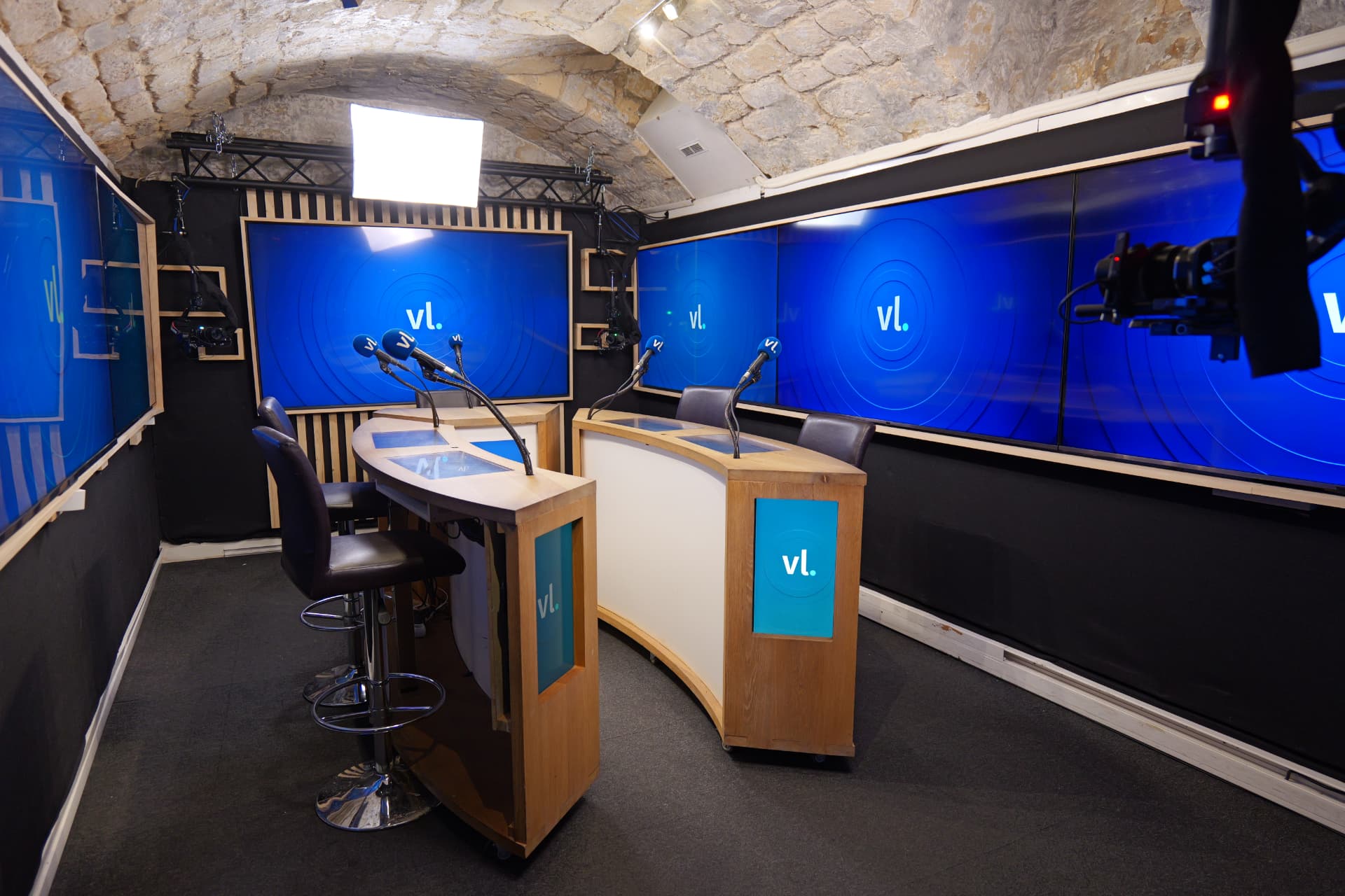 Plateau TV avec pupitres bois, micros et mur d'écrans LED en studio à Paris